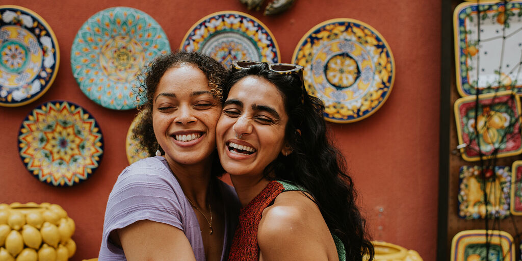 Fotos de vacaciones: dos personas posando juntas ante una pared decorada con cerámica artesanal durante un viaje.