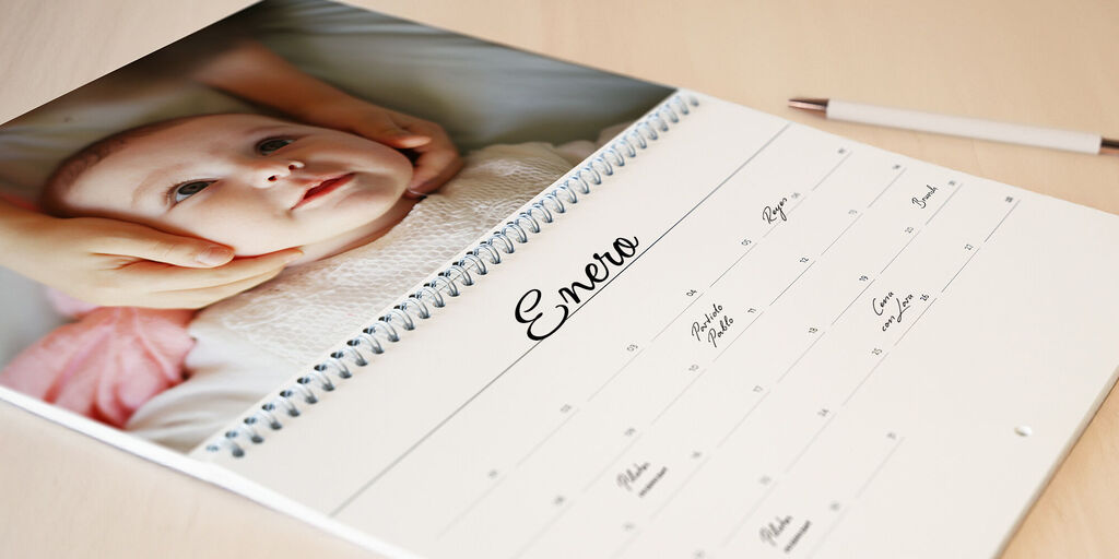 Un bebé adorable es sostenido con cariño por manos en un calendario fotográfico.