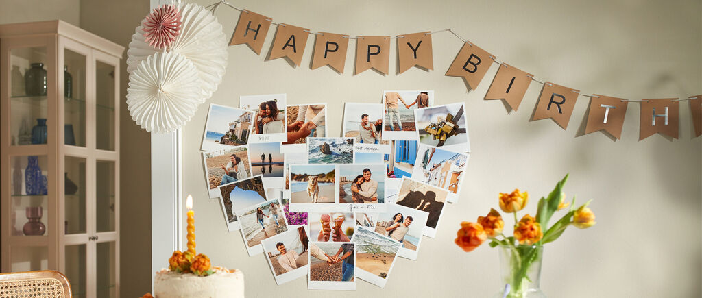 Una habitación decorada para un cumpleaños con fotos en forma de corazón y una guirnalda de cumpleaños.