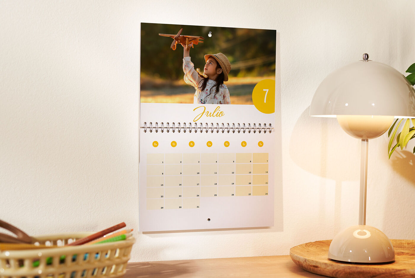 Un calendario de pared muestra un niño feliz con un avión de juguete. El mes de julio está resaltado.