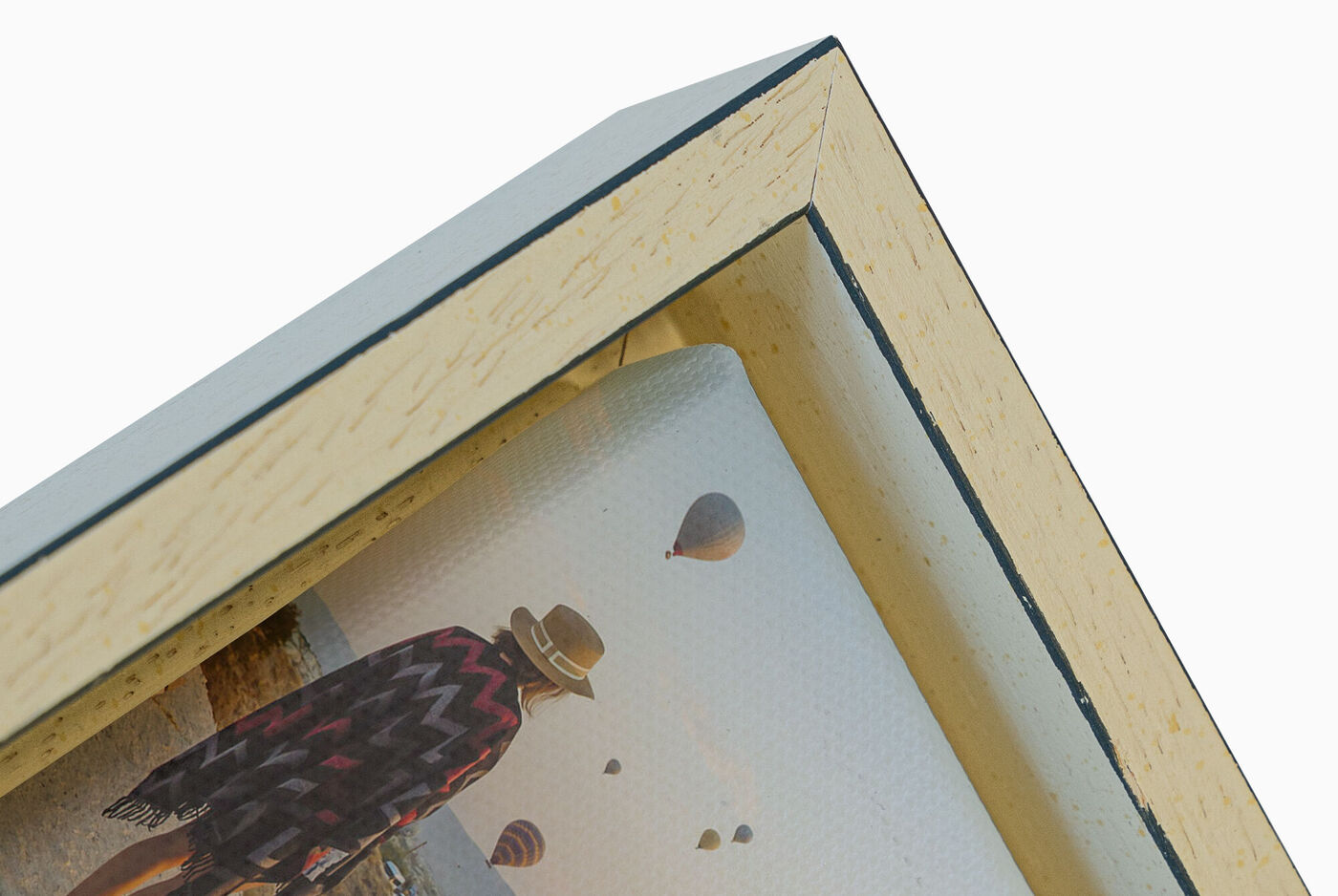 Vista detallada de un marco con una foto de una persona con sombrero y globos al fondo.