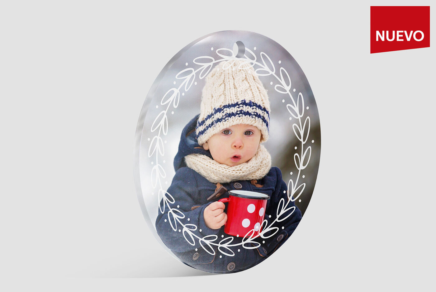 Un pequeño sostiene una taza roja, lleva un gorro y una bufanda. Fondo suave y desenfocado.