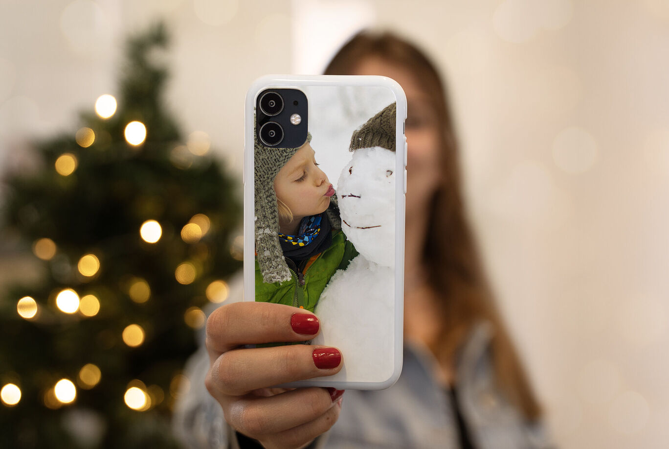 Persona sosteniendo un móvil con foto de un niño durmiendo en paisaje invernal.
