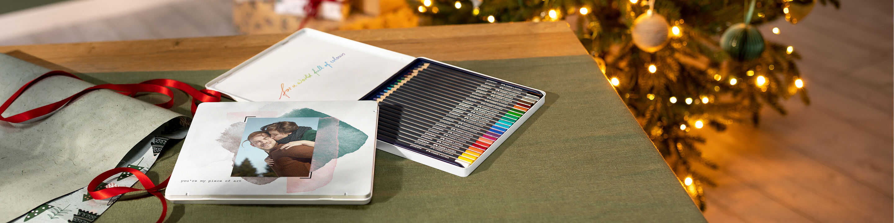 Un CEWE Fotobuch bellamente diseñado está sobre una mesa, rodeado de regalos y un árbol de Navidad decorado.