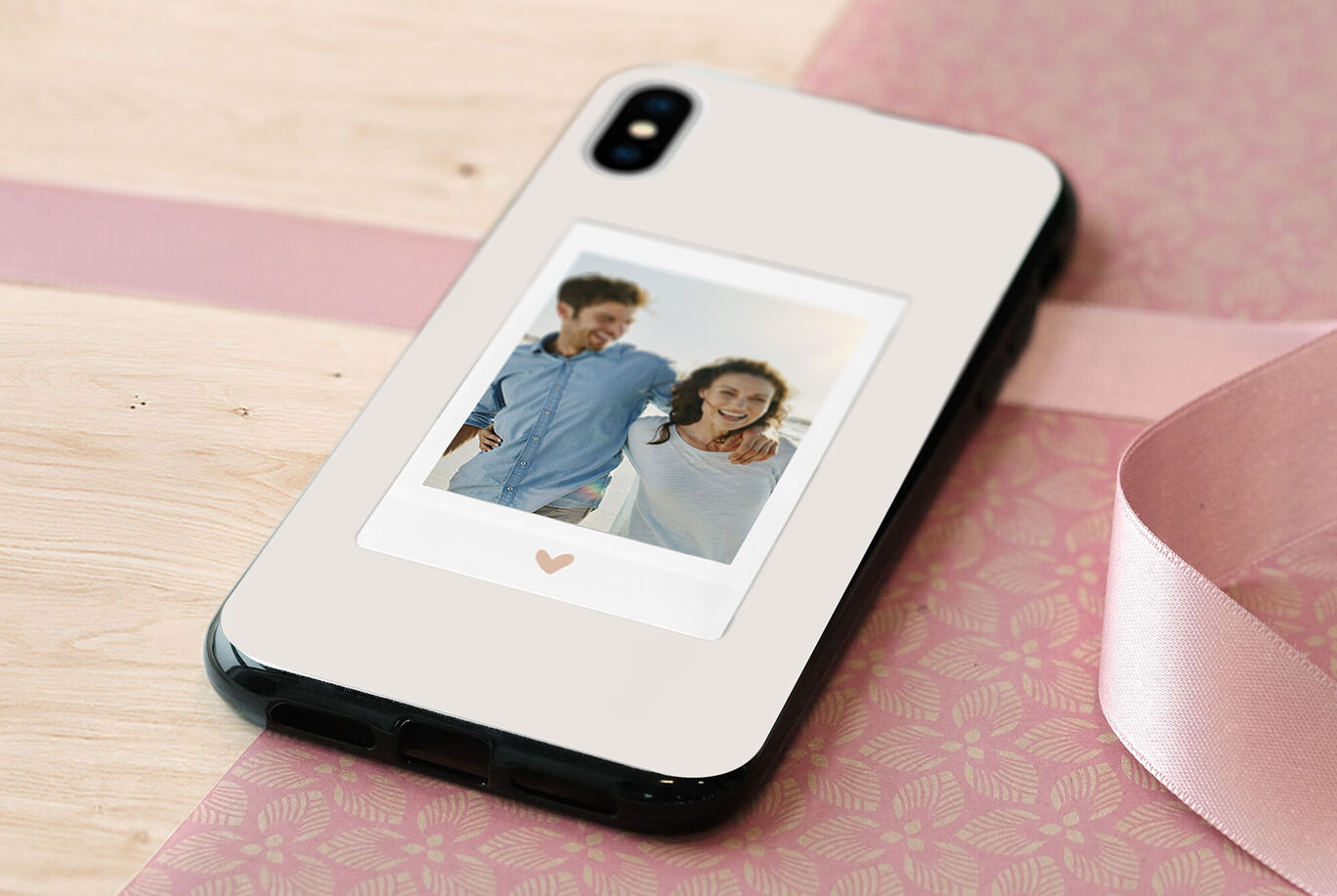 Móvil con funda de foto personalizada y motivo de corazón, sobre fondo de madera.