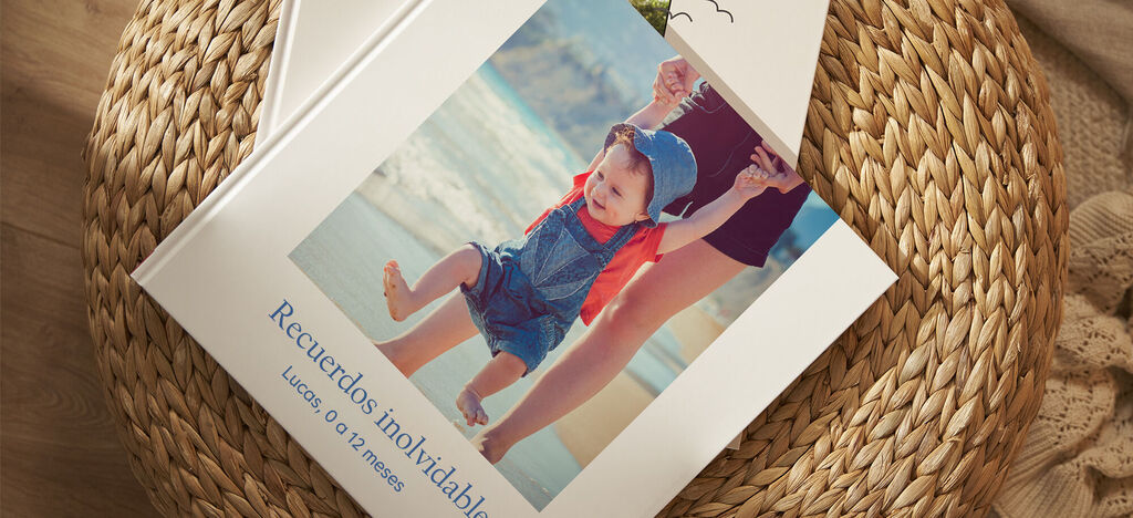 Un libro de fotos abierto con un niño feliz y una persona en la playa. La portada tiene el título en azul.