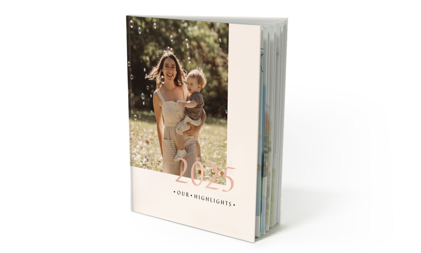 Un hermoso CEWE FOTOBUCH sobre una superficie blanca, con el título "2021 - NUESTROS MOMENTOS DESTACADOS"