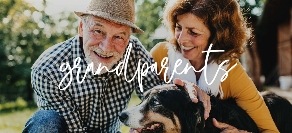 Una pareja mayor está sentada con su perro al aire libre, disfrutando del sol.
