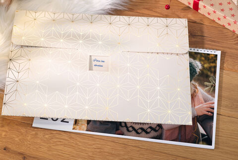 Un sobre cuidadosamente diseñado con un patrón dorado, rodeado de fotos y un calendario.