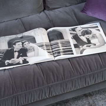 Un fotolibro abierto con hermosos momentos de una pareja en un sofá.