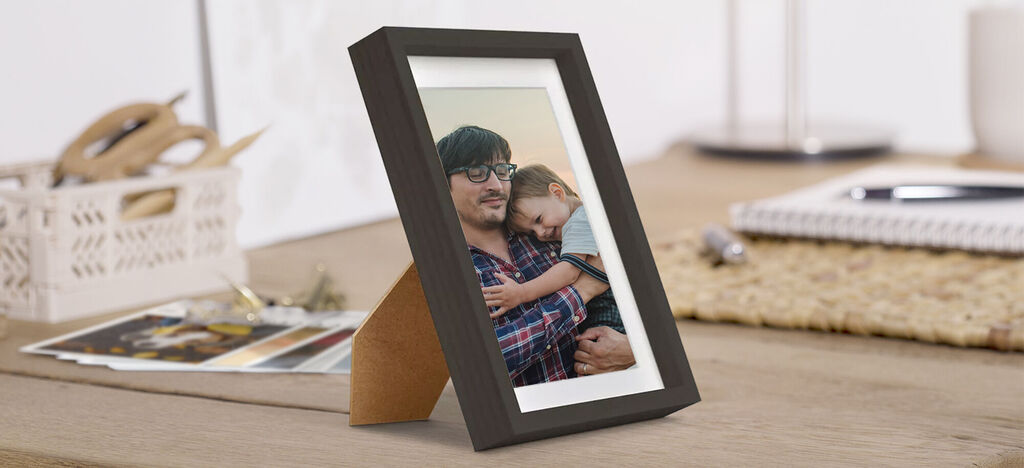 Una hermosa foto enmarcada sobre una mesa de madera, que muestra un abrazo cordial.