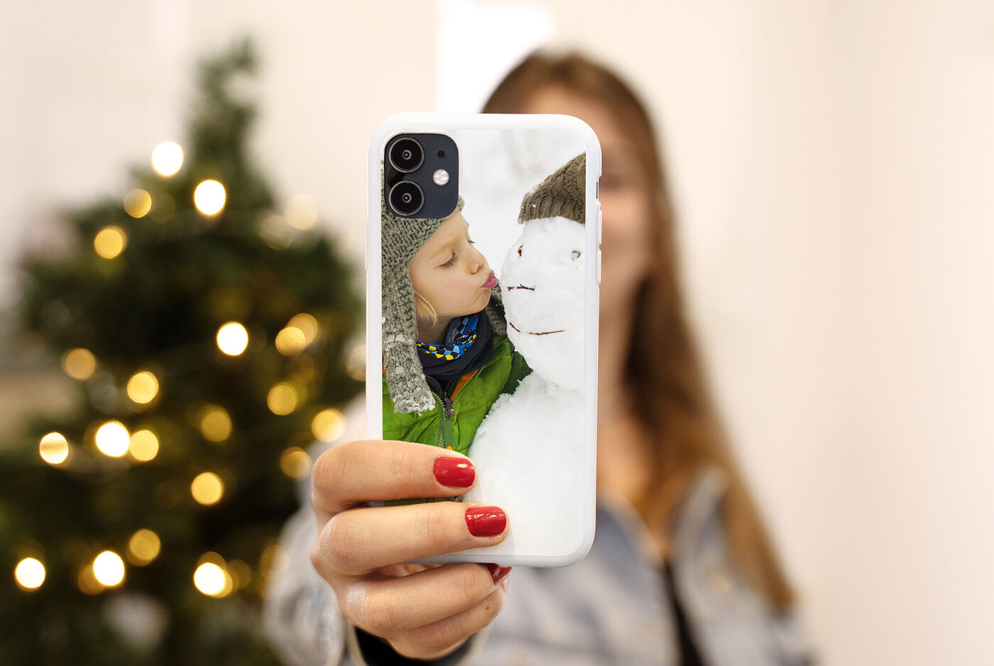 funda de móvil personalizada para hacer un regalo en navidad. Es una foto de invierno y se ve un arbol de Navidad de fondo.