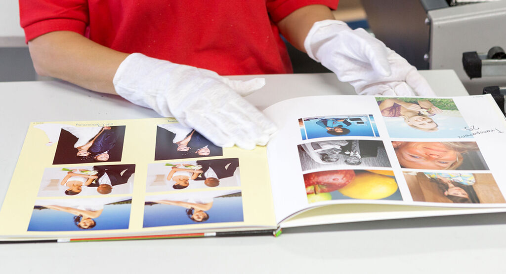 Una persona hojea un álbum de fotos CEWE con fotos de boda y frutas coloridas