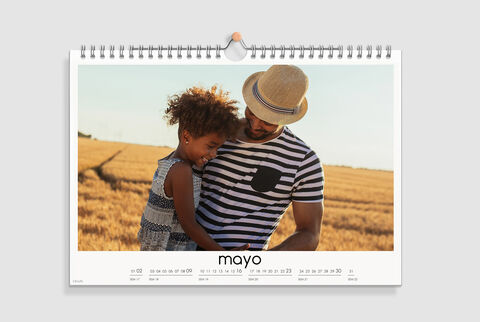 Un padre feliz sostiene a su hija en un amplio campo dorado. Disfrutan juntos del momento.