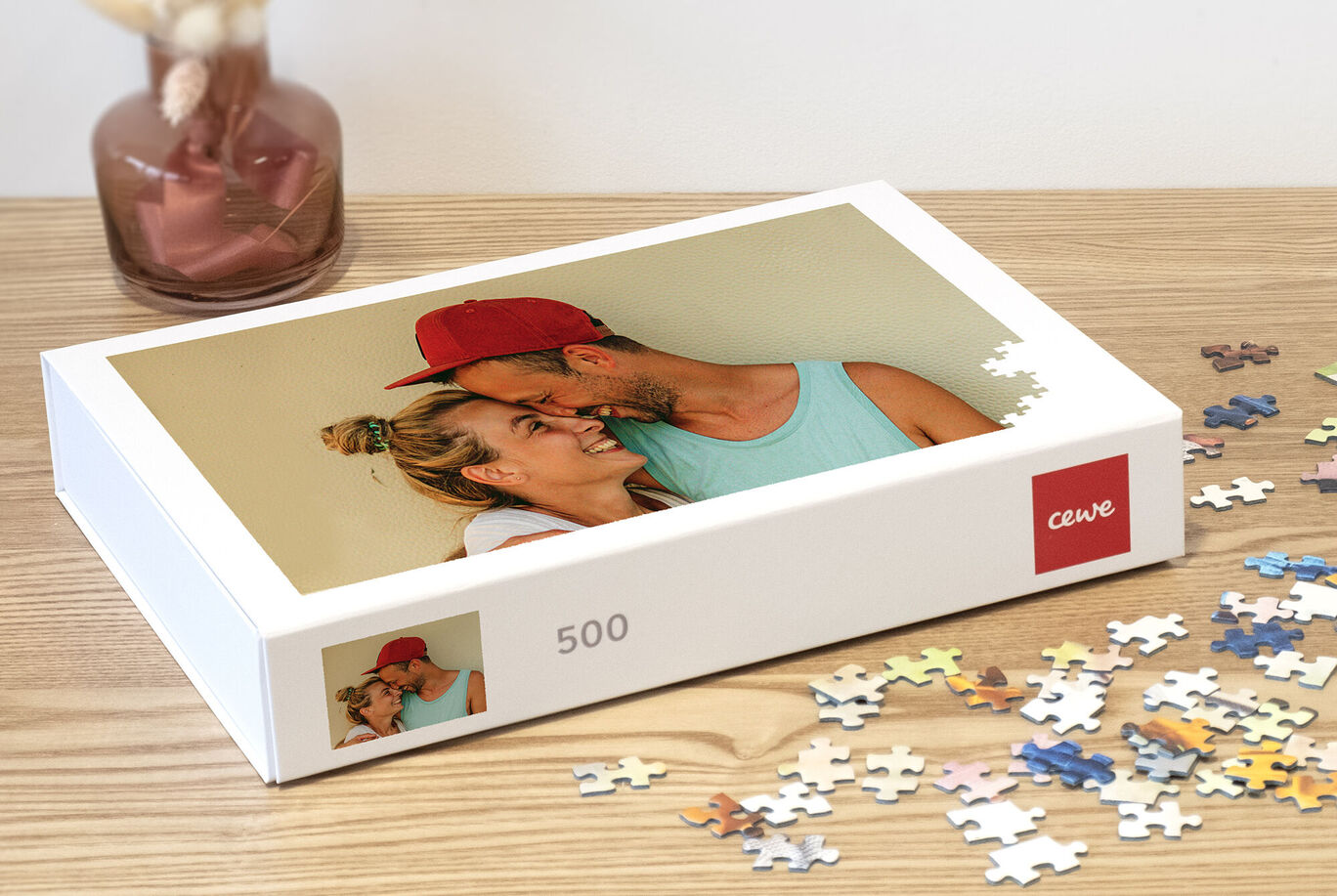 Caja de rompecabezas con una foto de una pareja y piezas de colores sobre una mesa.