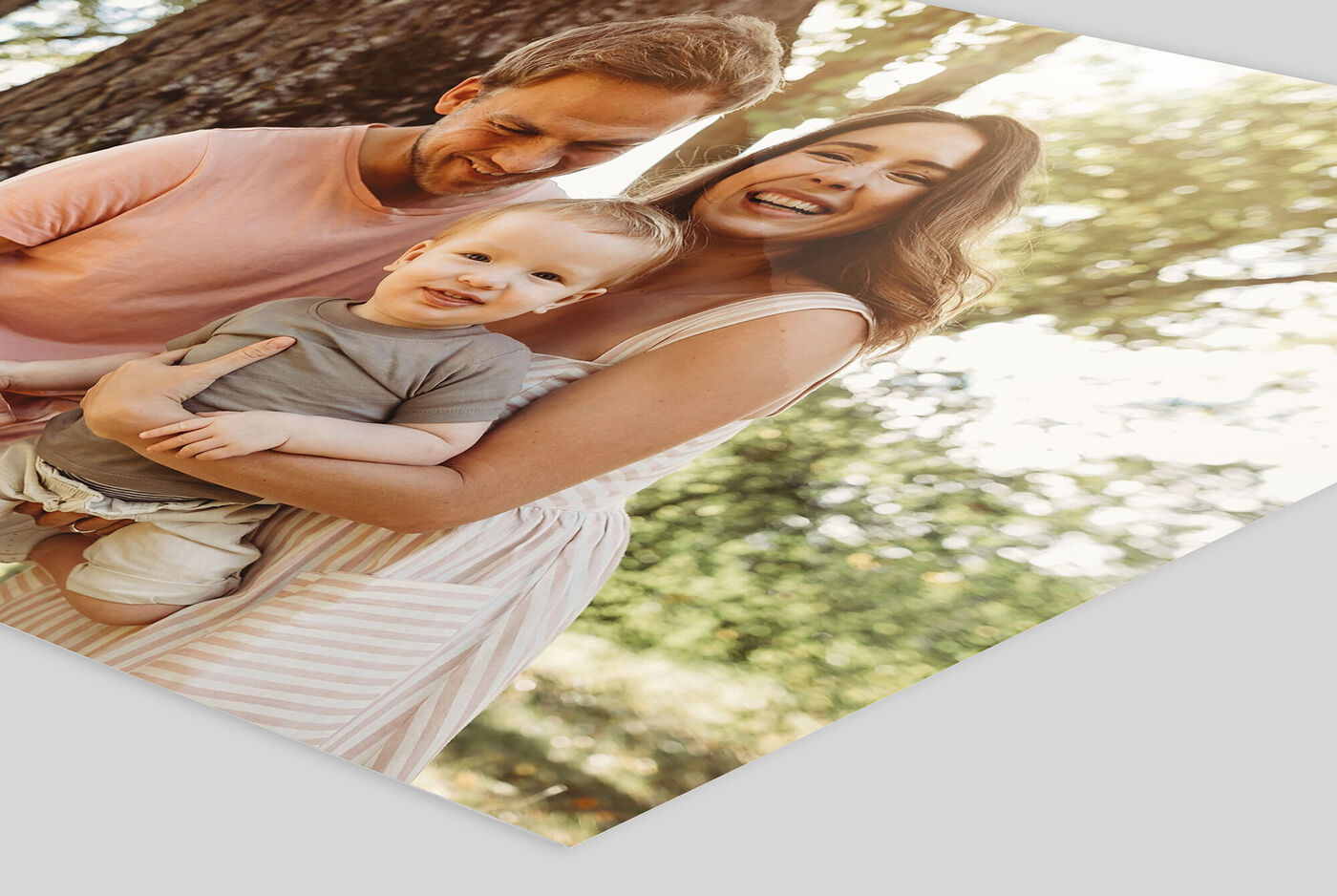 Una familia alegre al aire libre, riendo y disfrutando juntos. Un padre sostiene a un niño pequeño, sonriendo a la cámara.
