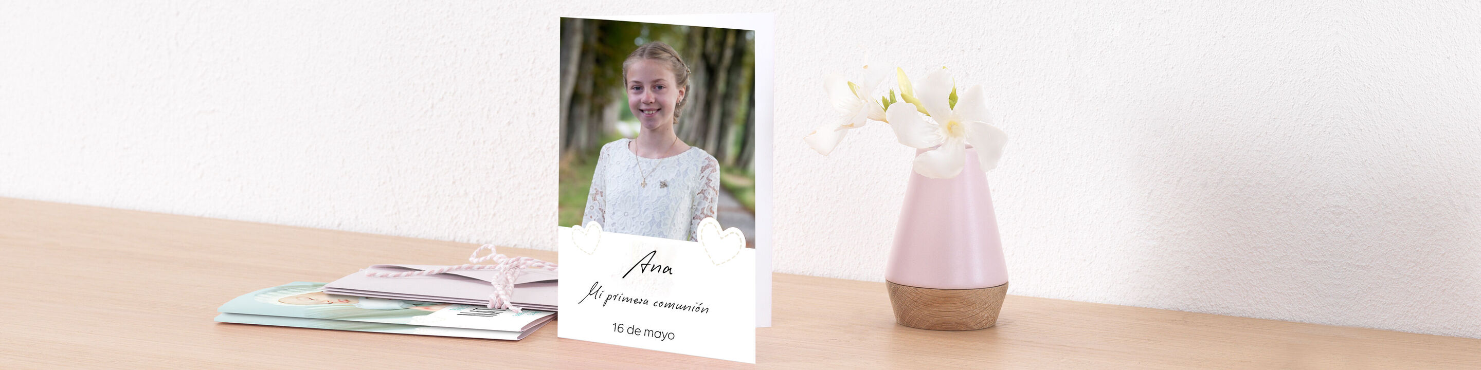 Una tarjeta de felicitación cuidadosamente diseñada de CEWE junto a un jarrón con flores sobre una mesa