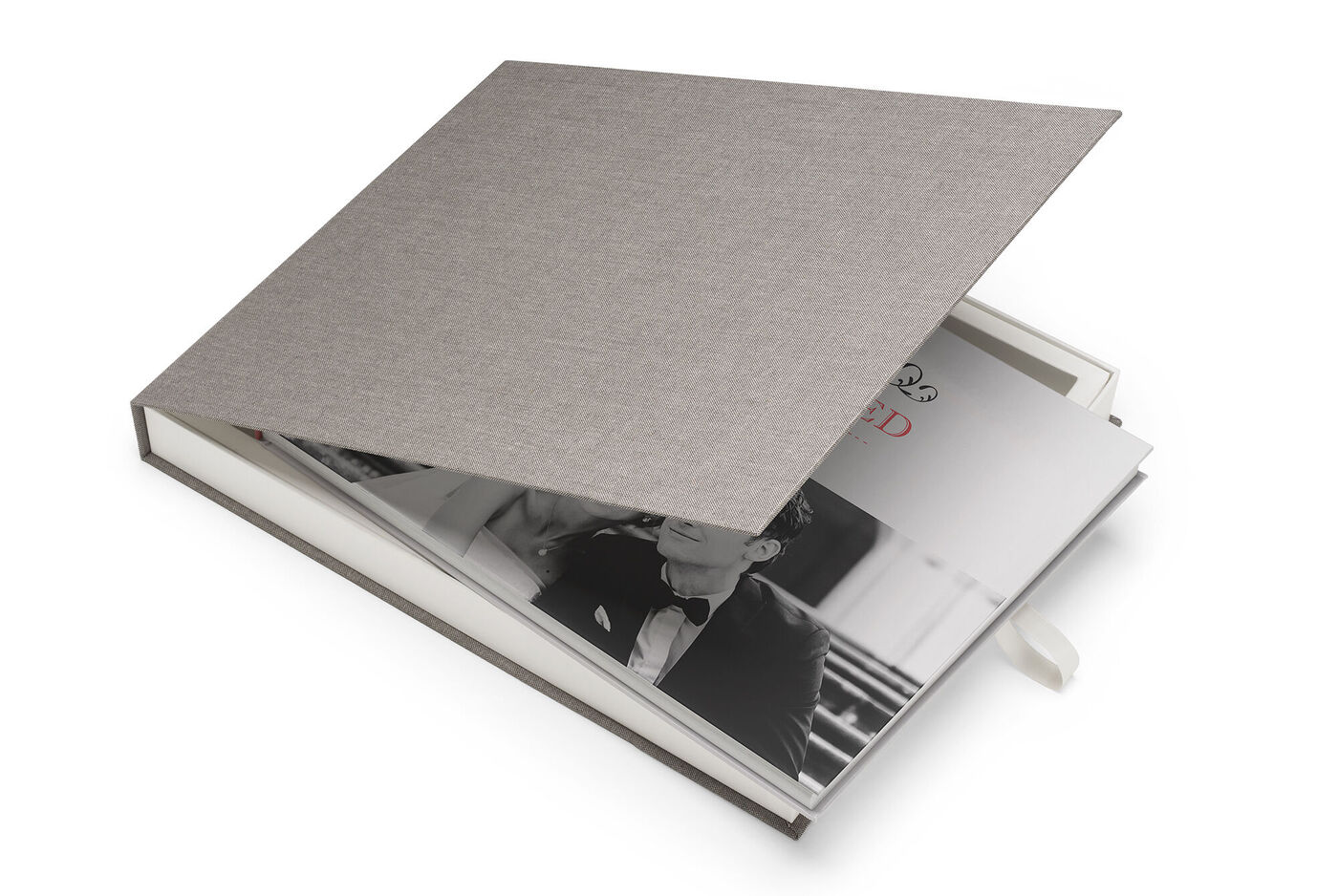 Un CEWE FOTOBUCH abierto con una elegante cubierta de tapa dura gris y una romántica foto en blanco y negro.