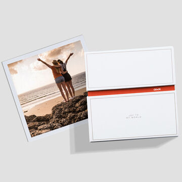 Dos amigas están en la playa disfrutando del momento. Con los brazos extendidos mientras las olas llegan suavemente a la orilla. CEWE FOTOLIBRO es visible.