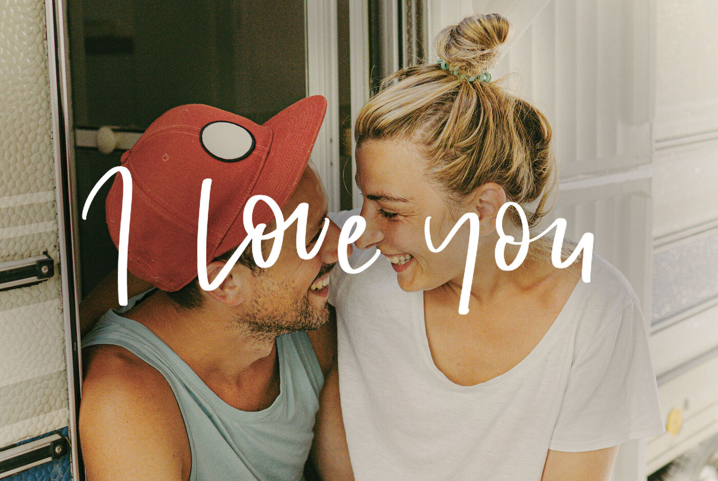 Una pareja sentada en una autocaravana disfrutando de un hermoso momento. Texto 'I Love You' arriba.