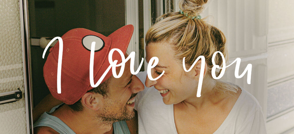 Pareja enamorada se mira y sonríe dentro de una autocaravana.