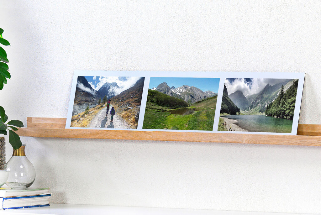 Tres fotos de paisajes en un marco moderno sobre una estantería. Muestran montañas, ríos y senderistas.