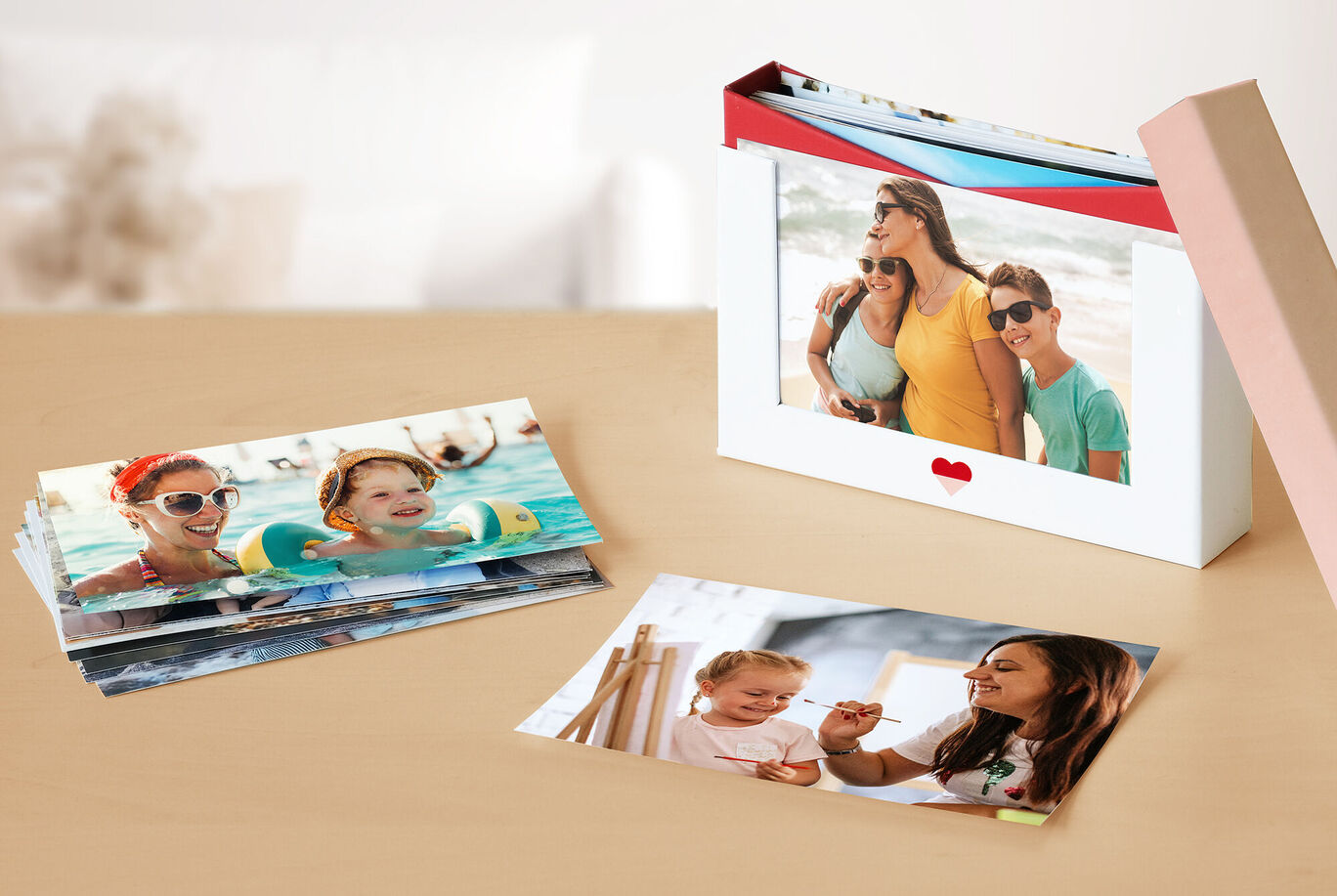Fotos coloridas sobre una mesa, un libro de fotos CEWE al lado que muestra un viaje familiar.