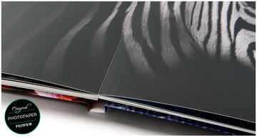 Primer plano de un álbum de fotos de alta calidad con páginas brillantes y una página doble de patrón de cebra en blanco y negro. CEWE FOTOLIBRO