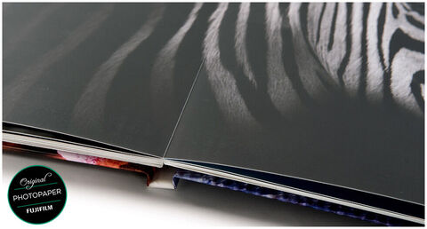 Primer plano de un álbum de fotos de alta calidad con páginas brillantes y una página doble de patrón de cebra en blanco y negro. CEWE FOTOLIBRO