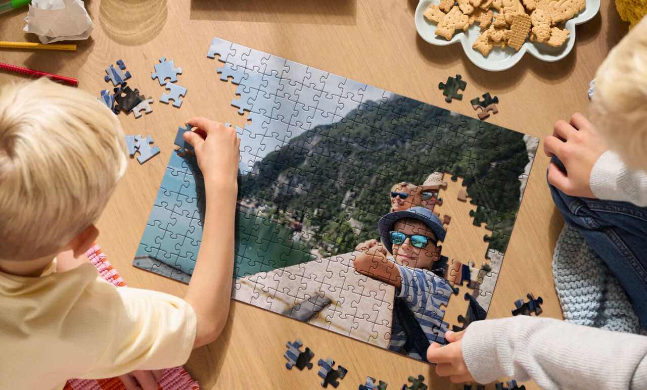 Primer plano de una persona armando un puzzle personalizado con foto de vacaciones, junto a su caja sobre una mesa