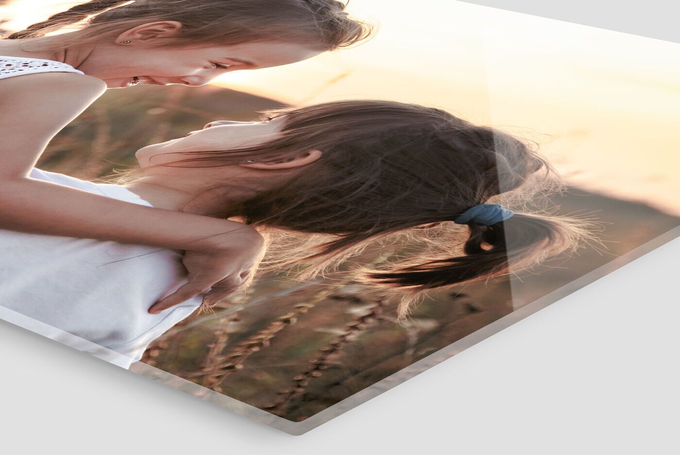 Dos niñas se miran y sonríen en un campo durante la puesta de sol.