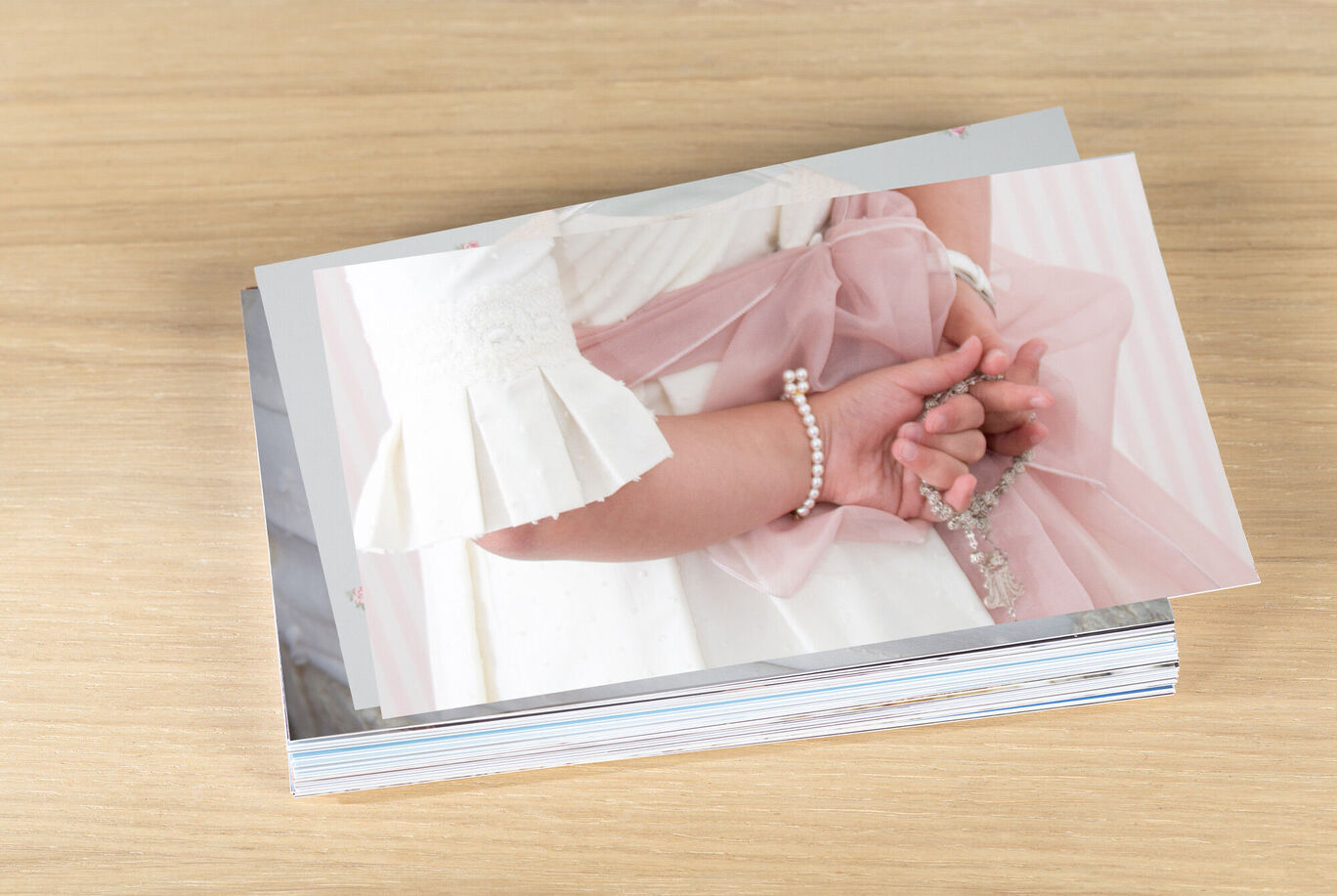 Fotos apiladas sobre fondo de madera, detalle de una mano con pulsera.