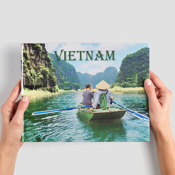 Dos personas reman en un bote en Vietnam con vegetación circundante y vista a la montaña.