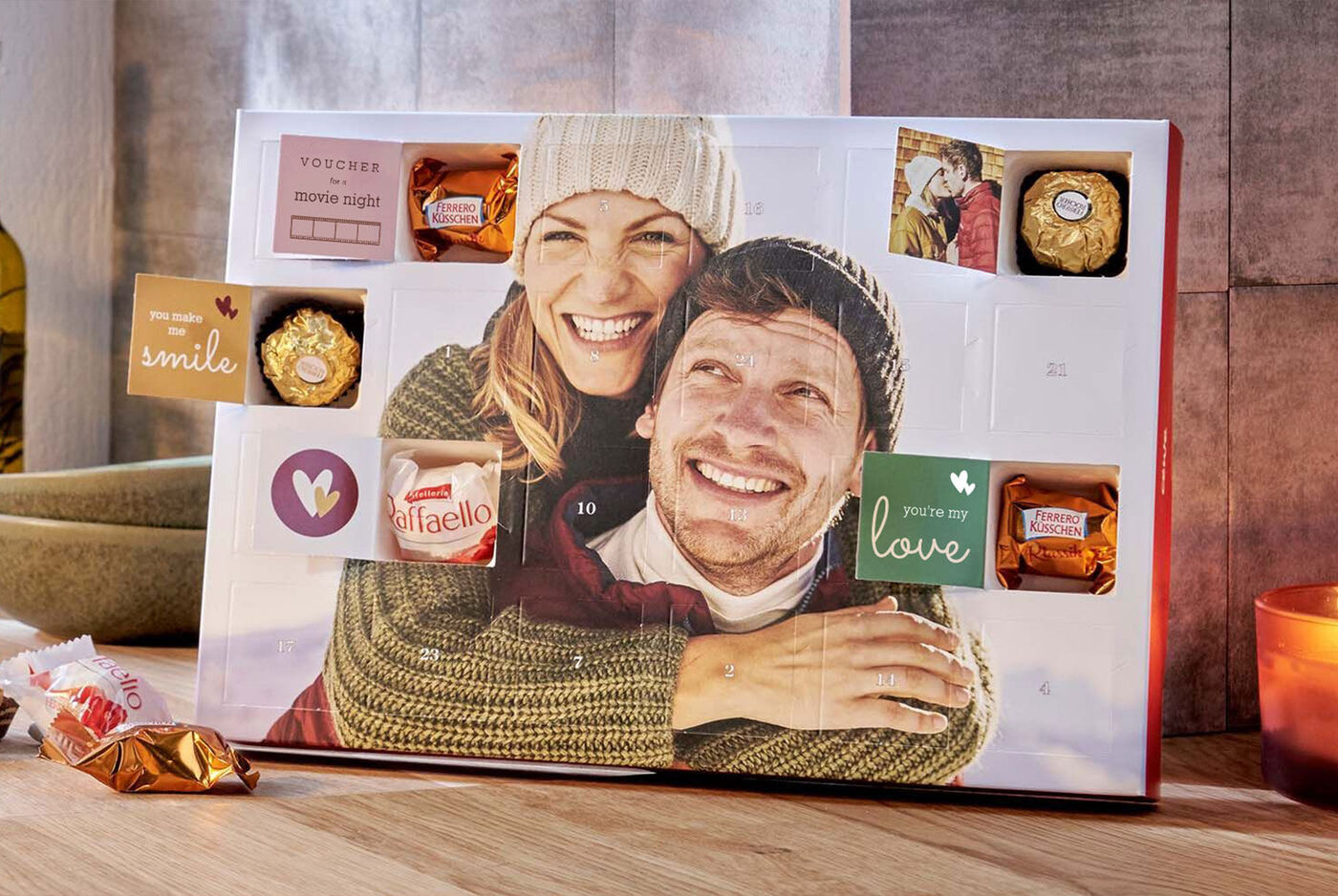 Caja de regalo personalizada con foto de pareja abrazada, decorada con chocolates y mensajes como "smile" y "love".