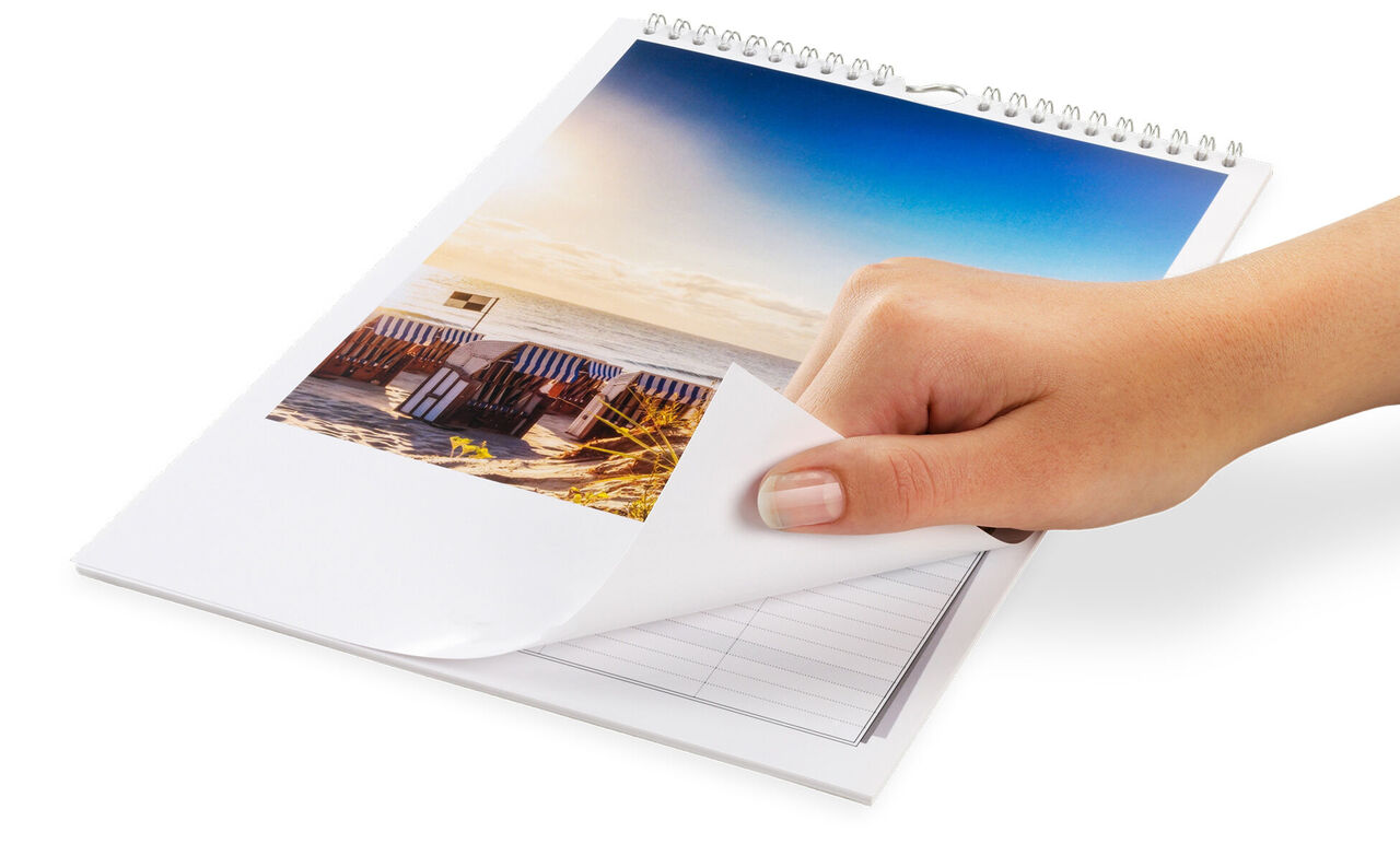 Una mano hojea un calendario fotográfico con hermosas fotos de paisajes.