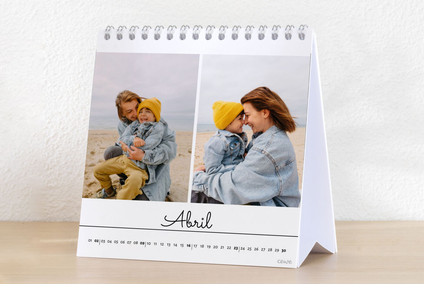 Dos personas posan sonriendo con un sombrero amarillo frente a un fondo de playa en un calendario CEWE.