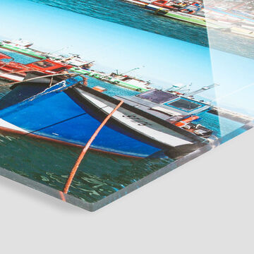 Un colorido barco balanceándose suavemente en el agua en un puerto con muchos otros barcos al fondo