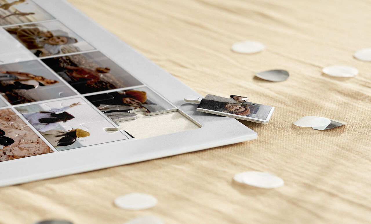 Un collage fotográfico creativo en un marco blanco sobre una tela elegante y clara. Alrededor hay piezas de confeti en forma de corazón.