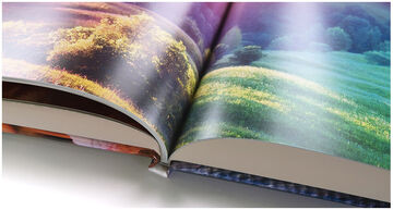 Hermoso CEWE Fotobuch abierto mostrando paisajes coloridos con campos verdes