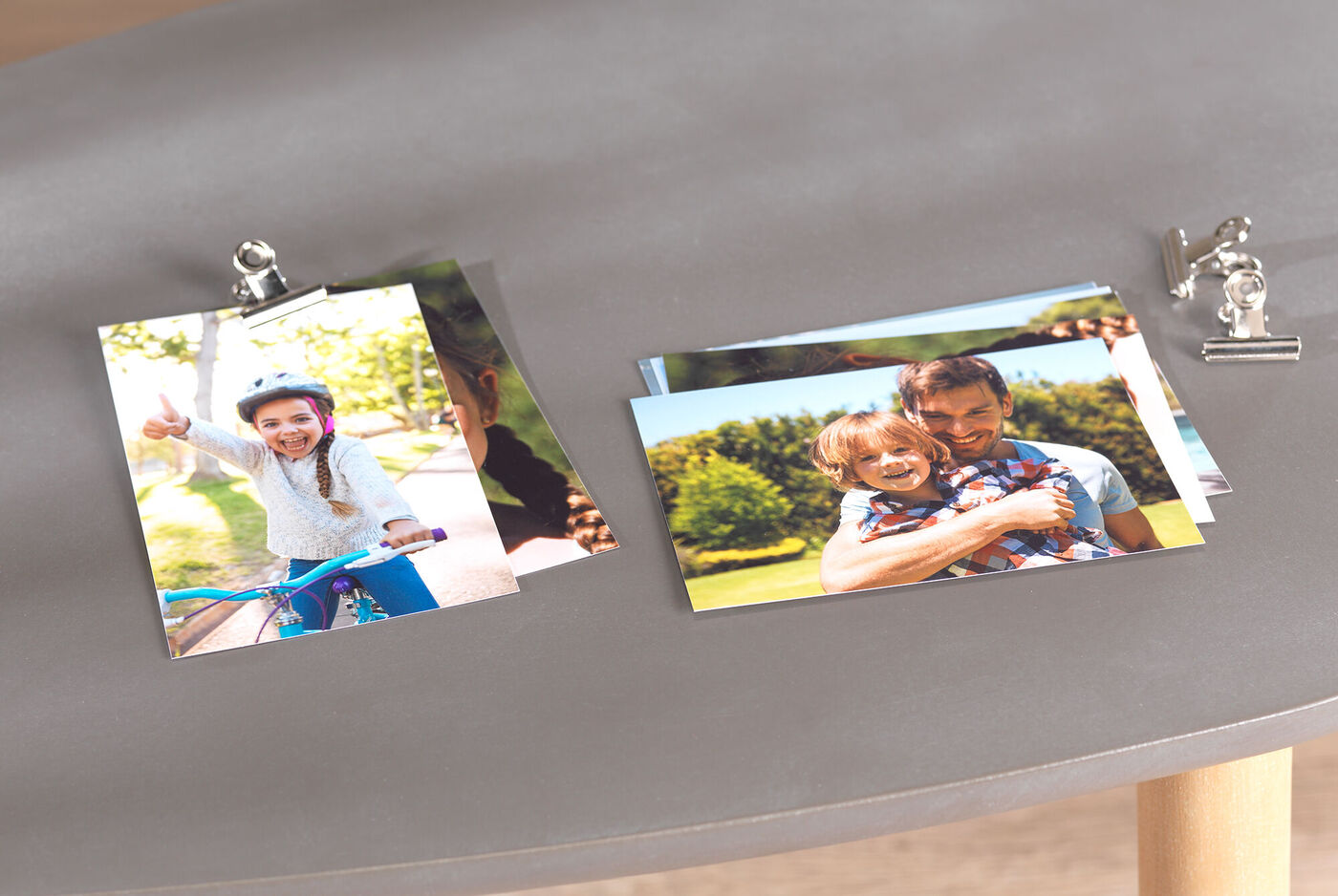Fotos coloridas se presentan sobre una mesa, incluyendo una imagen de un niño en bicicleta y otra de un adulto con un niño en brazos.