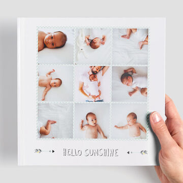 Bonito álbum CEWE con fotos de bebés sobre fondo claro.