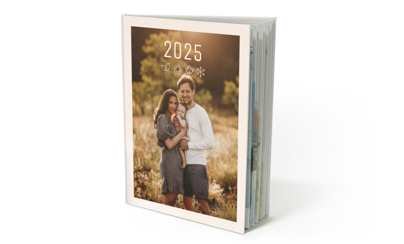 Un CEWE FOTOLIBRO amorosamente diseñado con el año 2024 en la portada, mostrando una familia feliz al aire libre.