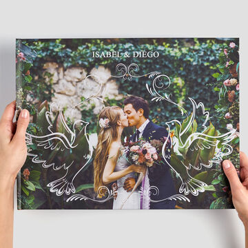 Pareja sostiene álbum CEWE con motivos florales.