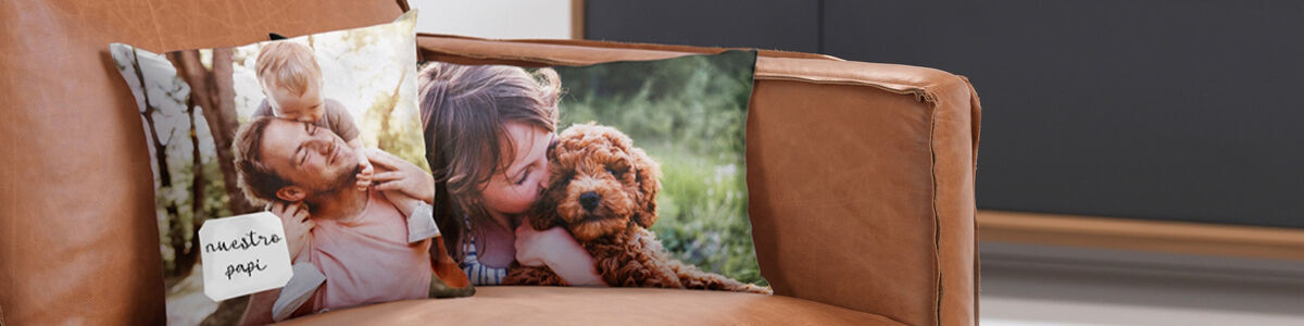 Dos cojines con impresiones fotográficas en un sofá. Uno muestra a una familia feliz, el otro a un niño con un perro.