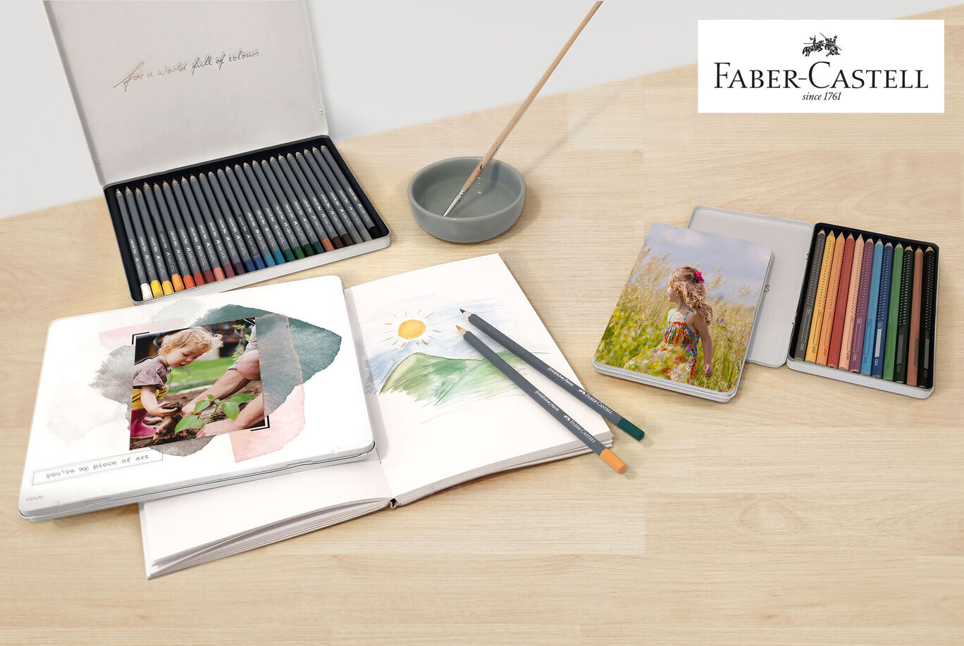Una mesa creativamente decorada con materiales de Faber-Castell, un fotolibro y fotos.