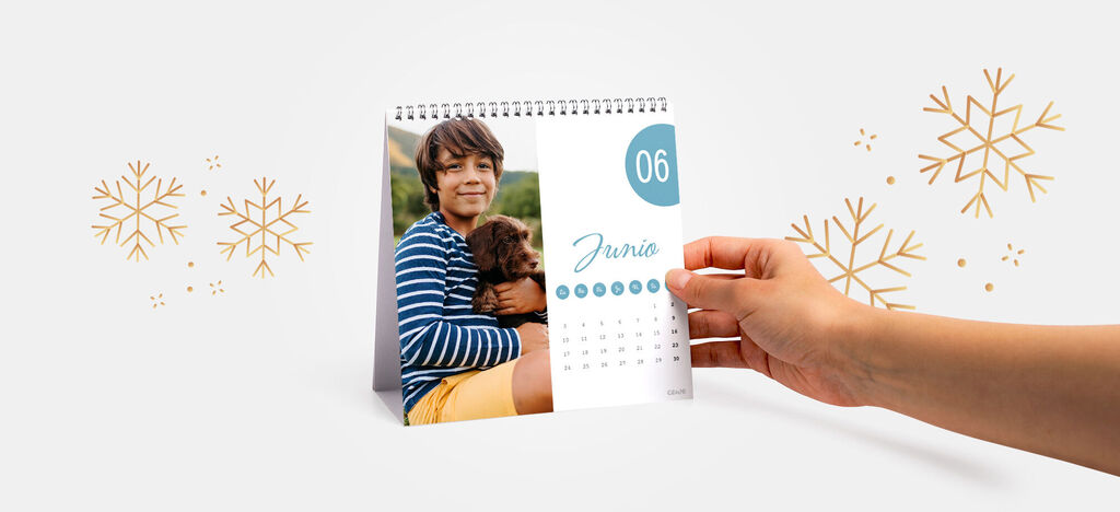 Una mano sostiene un calendario CEWE con la imagen de un niño y un perro.