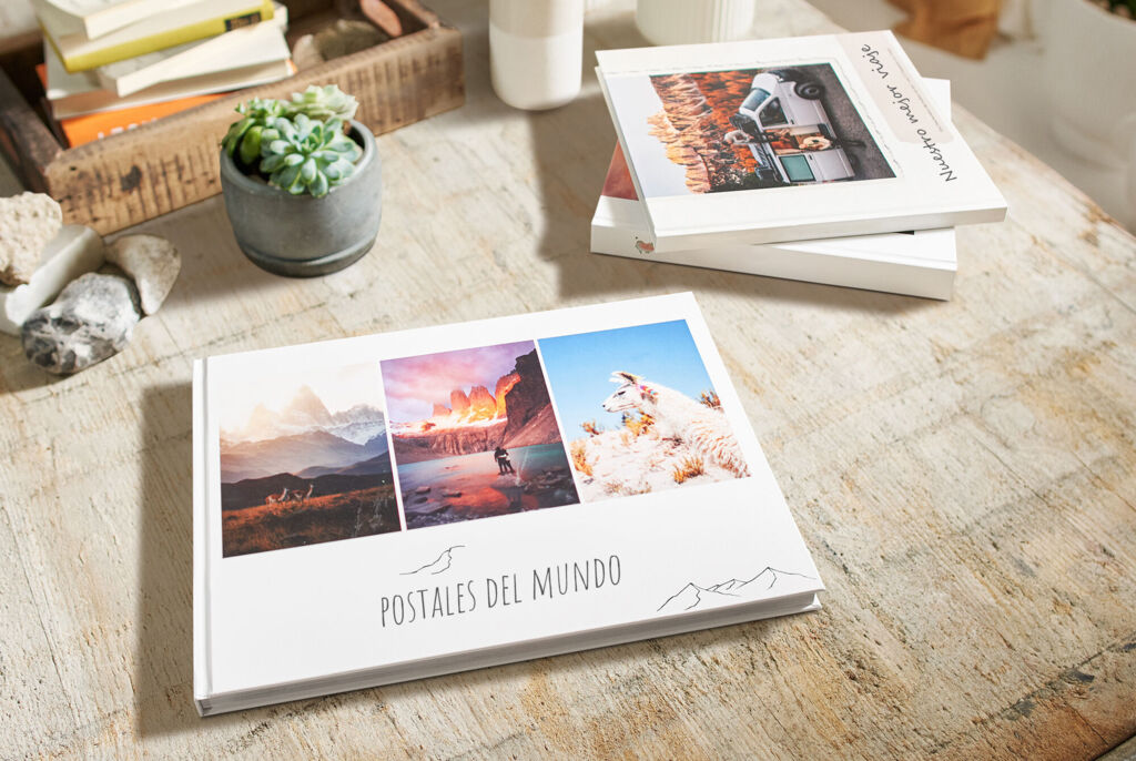 Álbum de fotos 'Postales del Mundo' sobre una mesa con varias fotografías de paisajes.