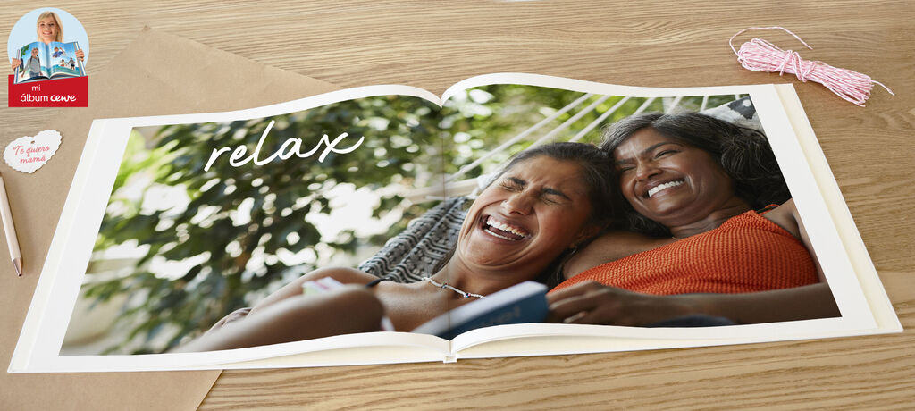 Doble página de un CEWE FOTOBUCH abierto con la palabra "relax" en caligrafía. Colores cálidos y ambiente relajante.