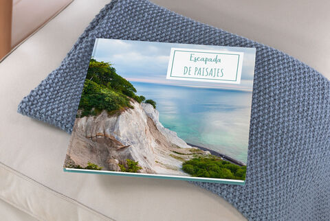 Un libro de fotos CEWE sobre un sofá con una imagen de paisaje hermosa.