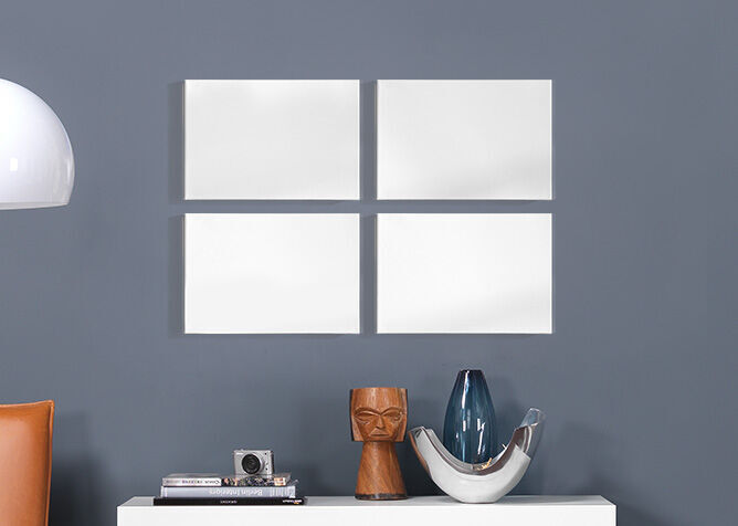 Marcos vacíos blancos en una pared gris, decorados con elegantes jarrones y una cámara.